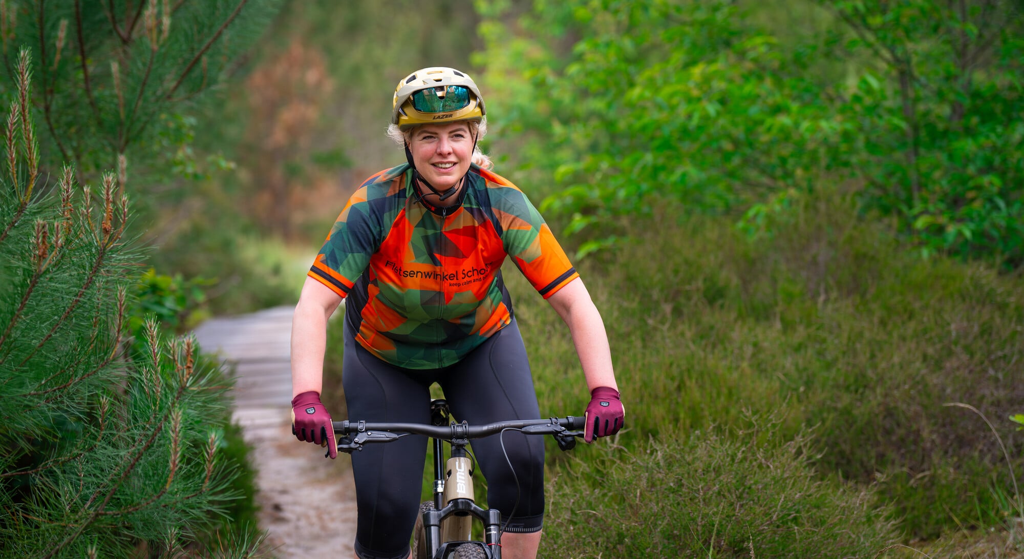 Mountainbikester rijdt lachend over het plankenpad in de Schoorlse duinen