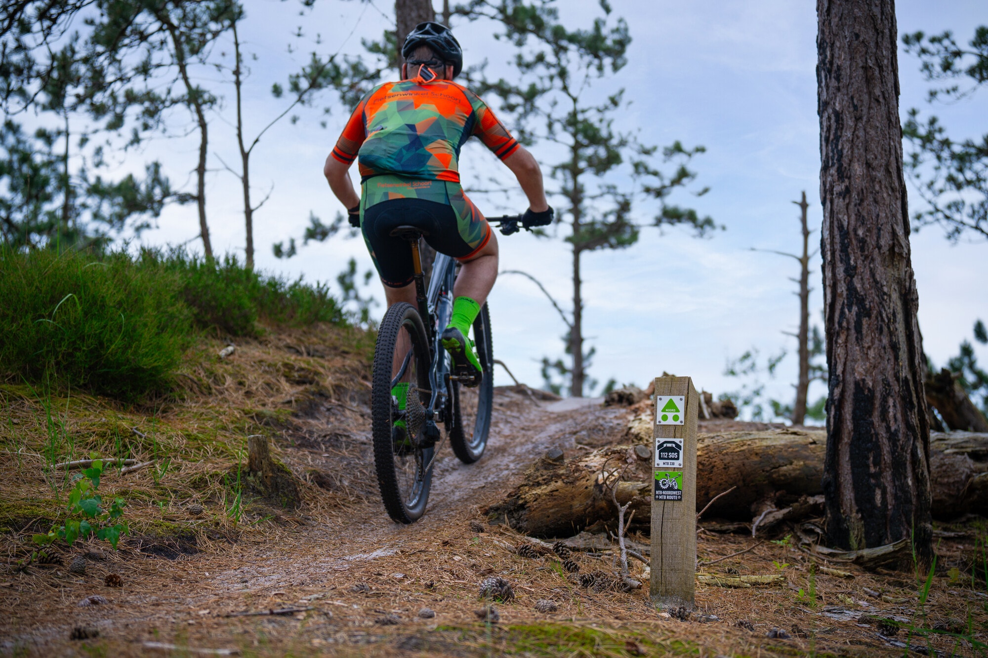 Mountainbiker klimt een heuvel op langs een routepaaltje
