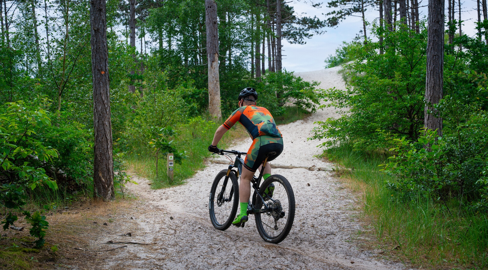Mountainbiker rijdt over een zanderig pad in de Schoorlse duinen