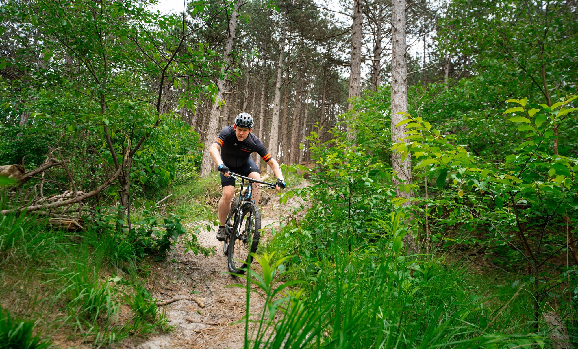 Mountainbiker daalt gecontroleerd af over een smal pad in de Schoorlse duinen