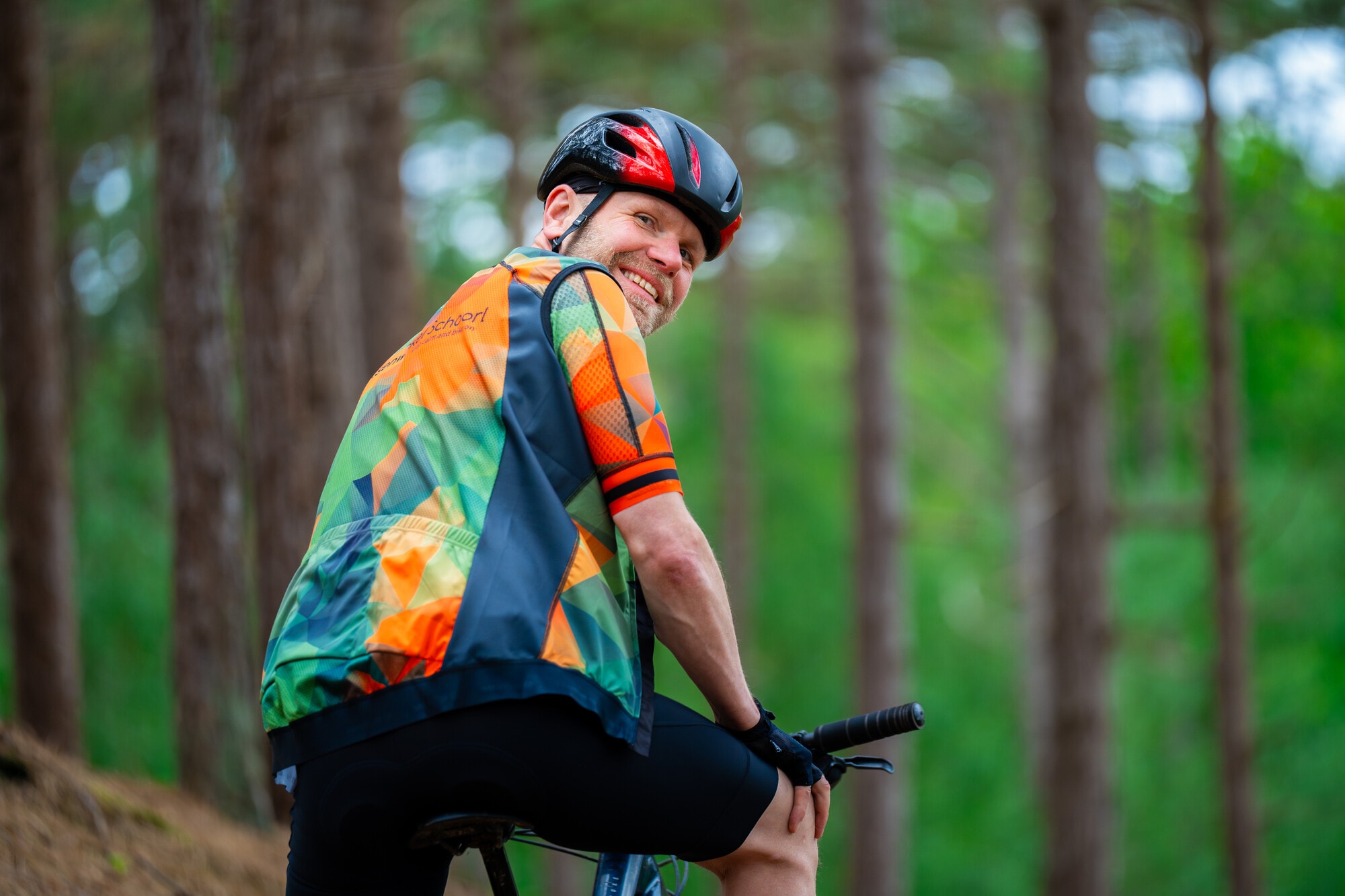 Ontspannen mountainbiker kijkt lachend om vanaf zijn fiets