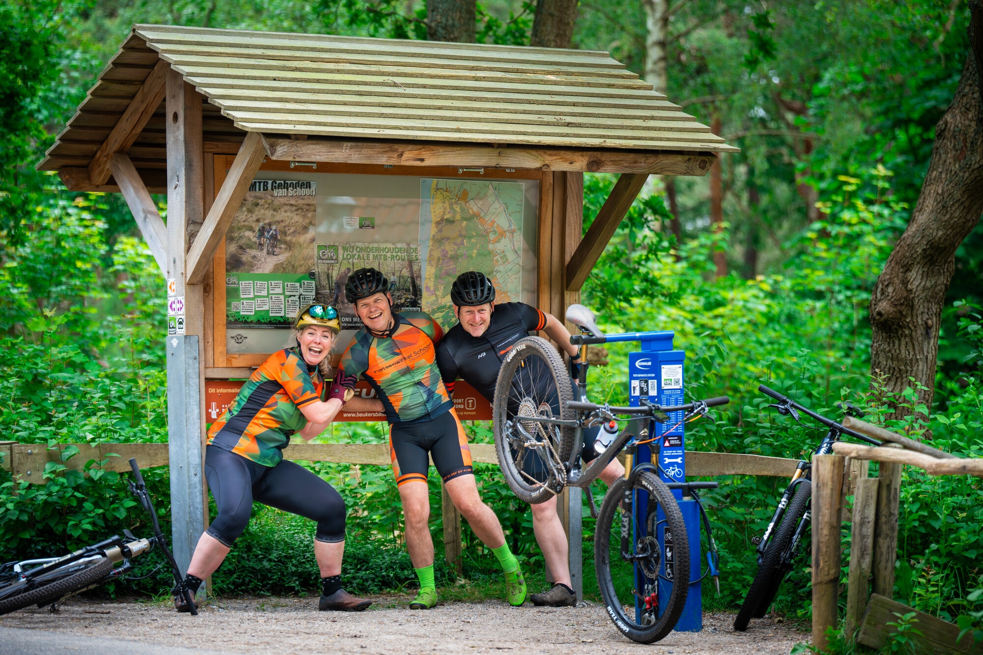 Drie lachende mountainbikers bij het informatiebord van de MTB-route in Schoorl